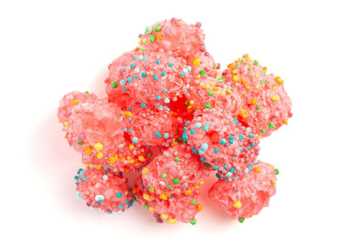 A pile of pink candy with sprinkles on a white background.