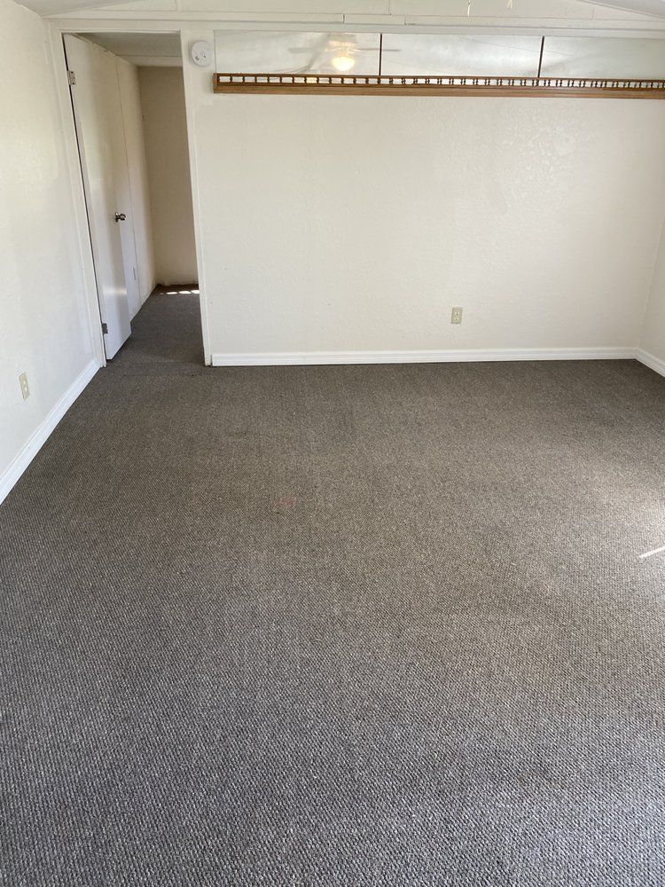 an empty living room with a gray carpet and white walls