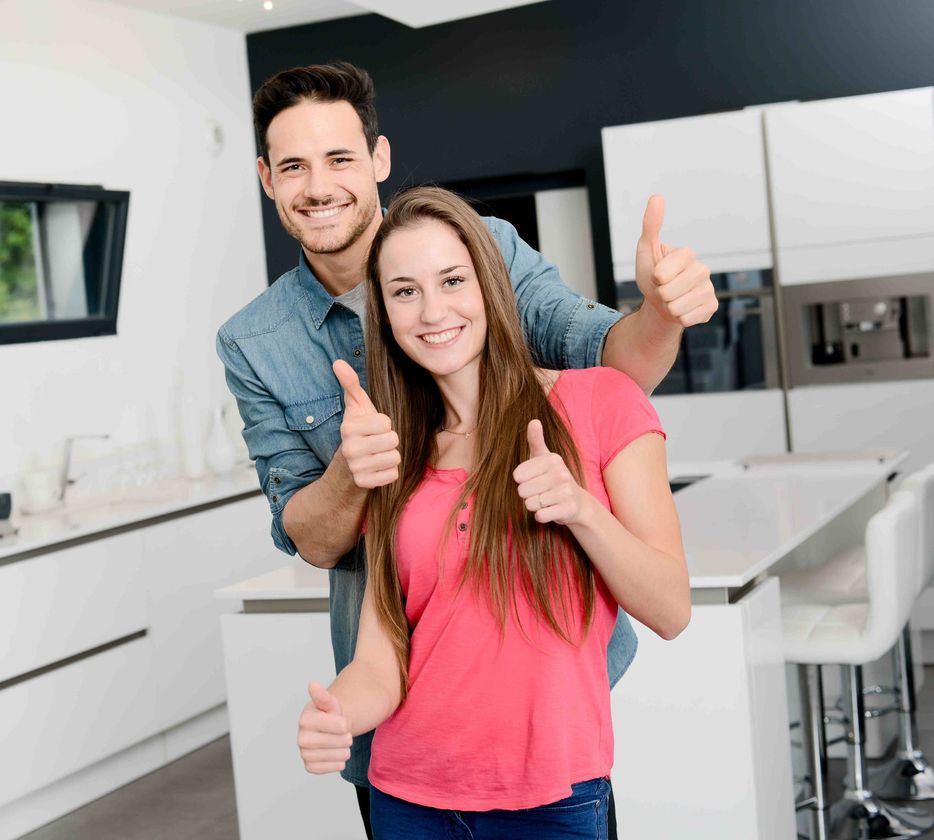 a man and a woman are giving a thumbs up in a kitchen