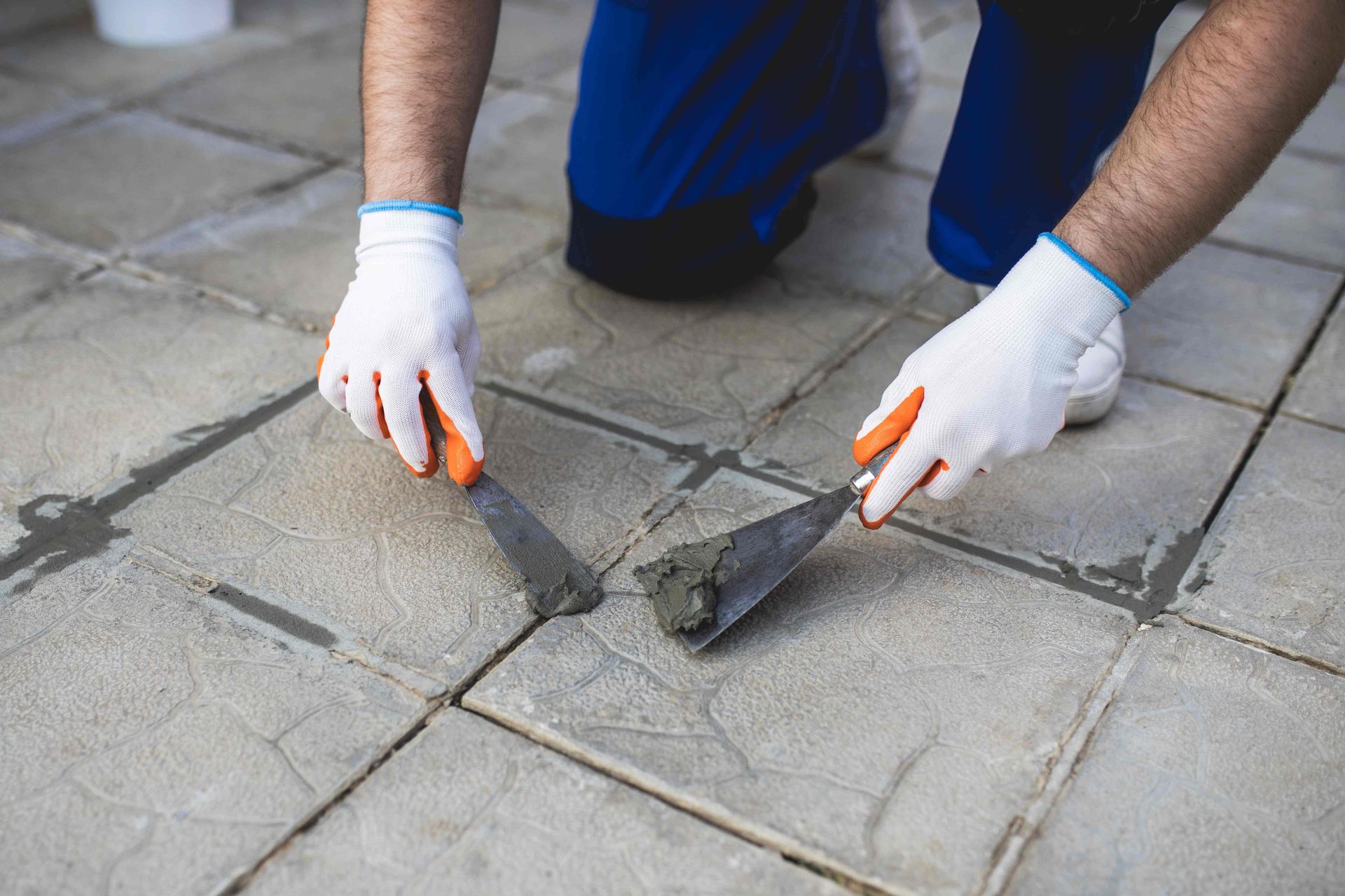 a man is using a spatula to spread concrete on a tiled floor