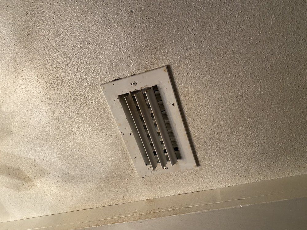 a white air vent is hanging from the ceiling of a room