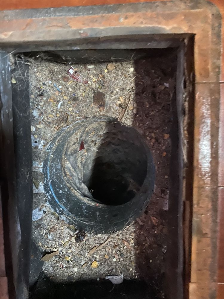 A dirty drain with a hole in the middle of it.