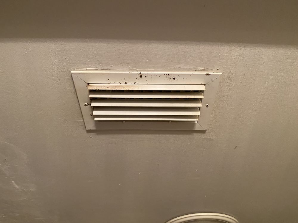 a white air vent is hanging from the ceiling in a bathroom