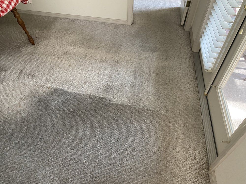 A dirty carpet in a room next to a door.
