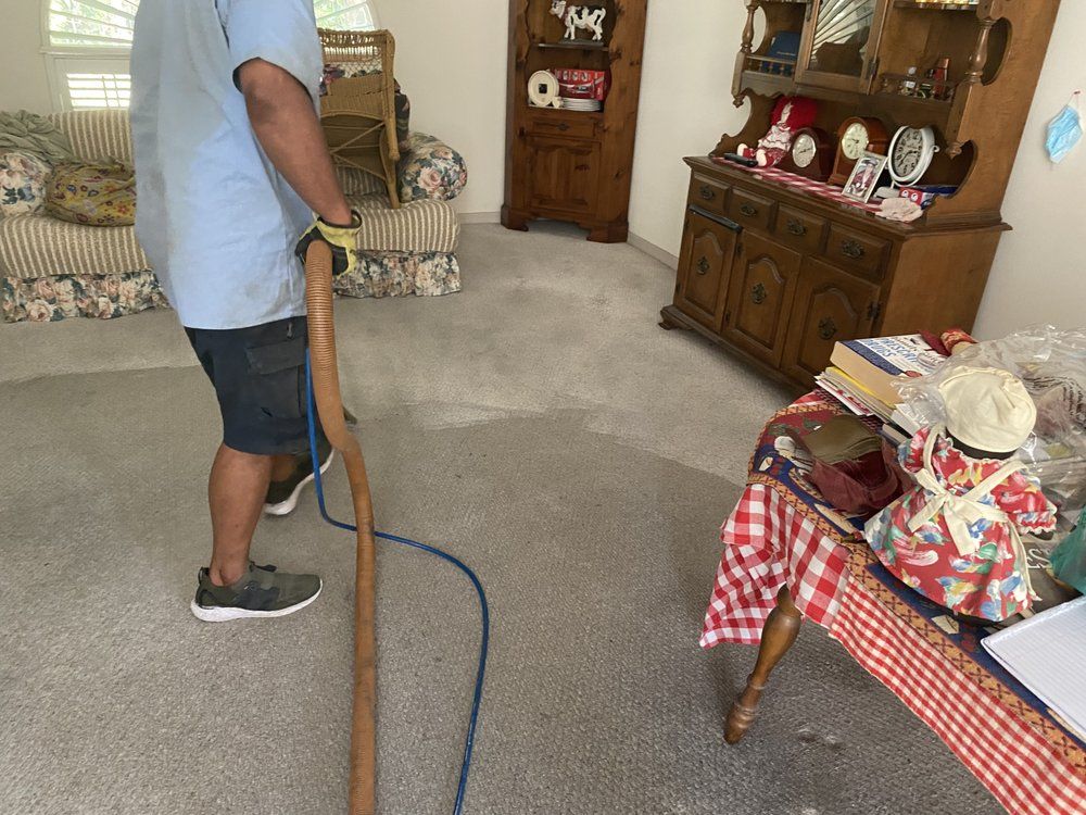 A man is using a vacuum cleaner to clean a carpet in a living room.