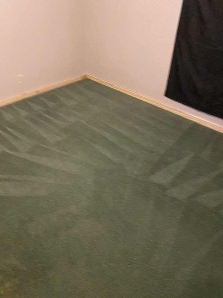 A room with a green carpet and a black curtain.