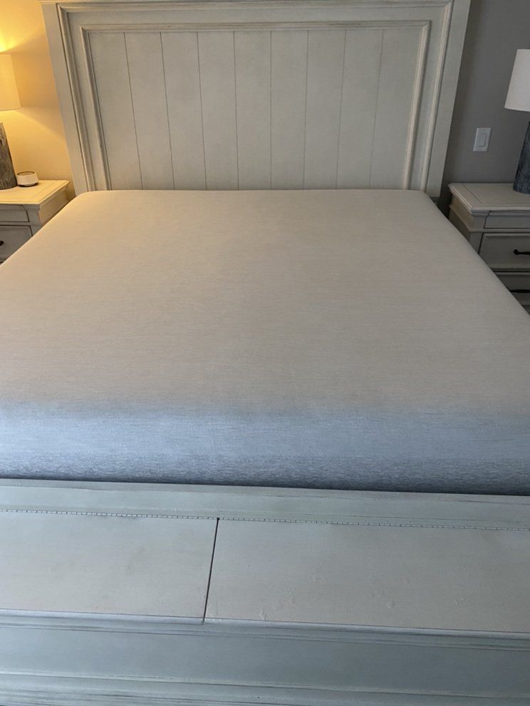 a bed with a white headboard and a white mattress in a bedroom