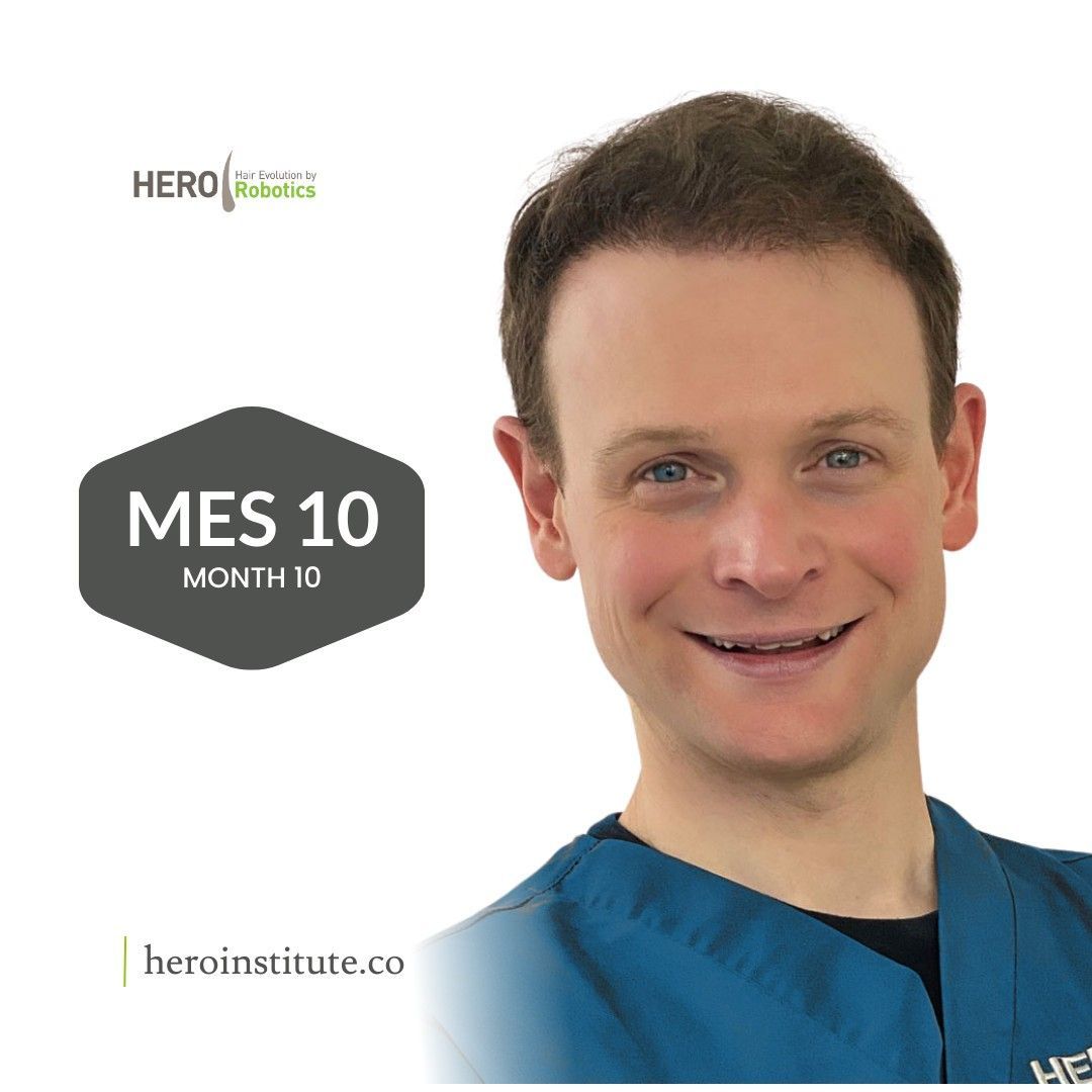 A man is smiling in front of a mes 10 month sign