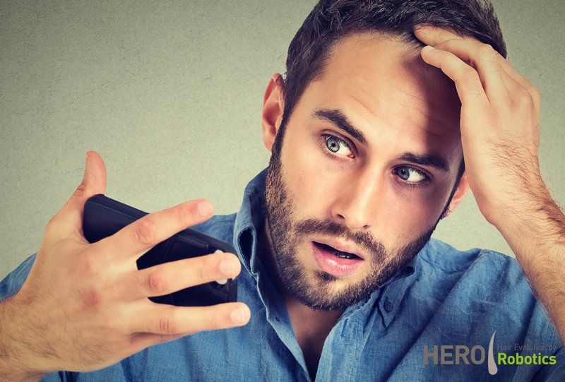 a man in a blue shirt is looking at his cell phone .