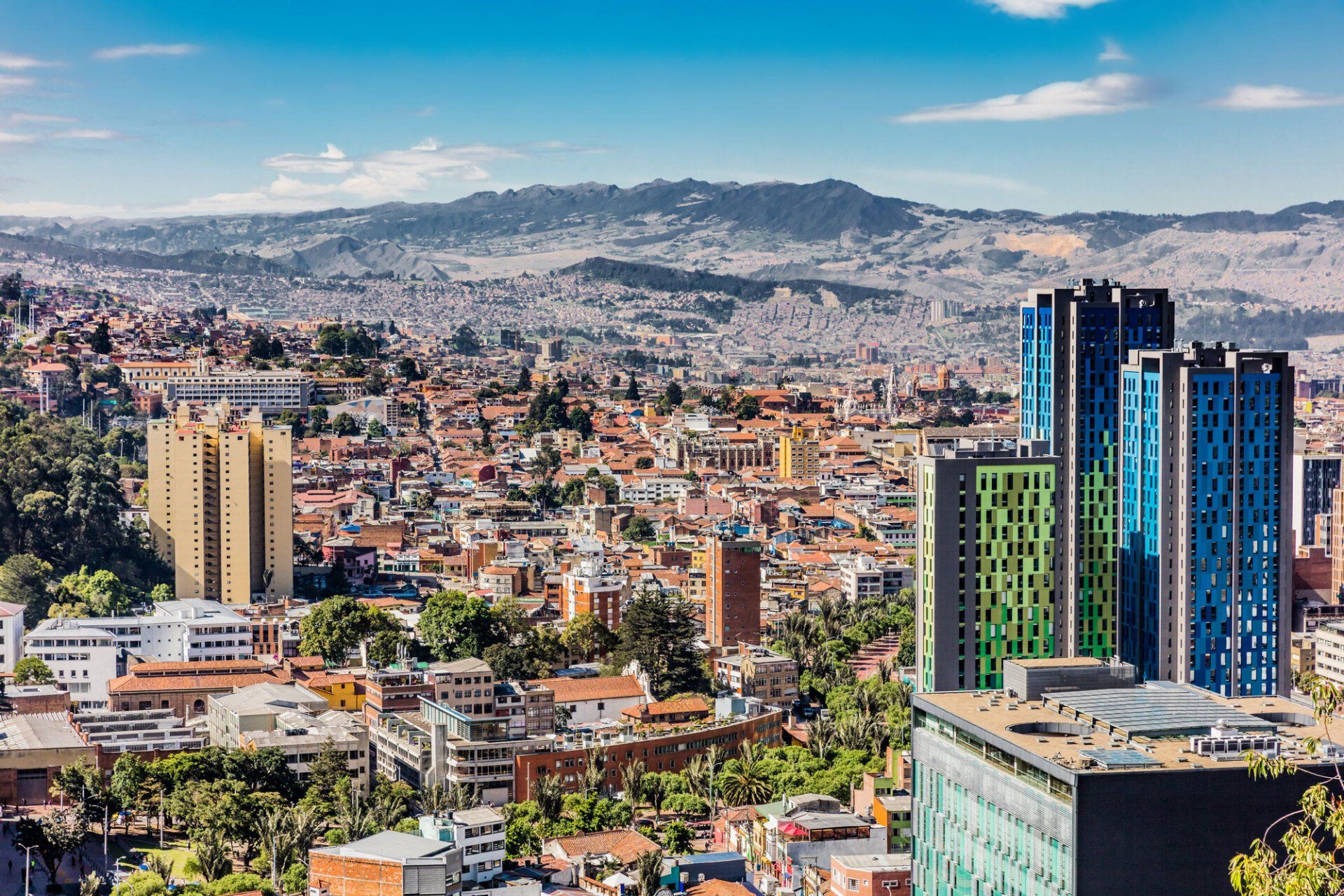 Cityscape of Bogotá, Colombia, with modern skyscrapers and residential buildings against a mountain backdrop.