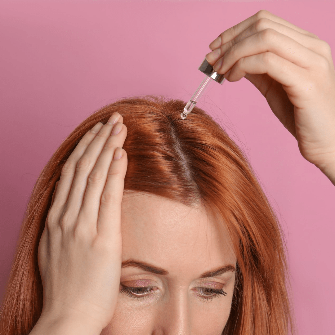 a woman is applying a dropper to her hair .