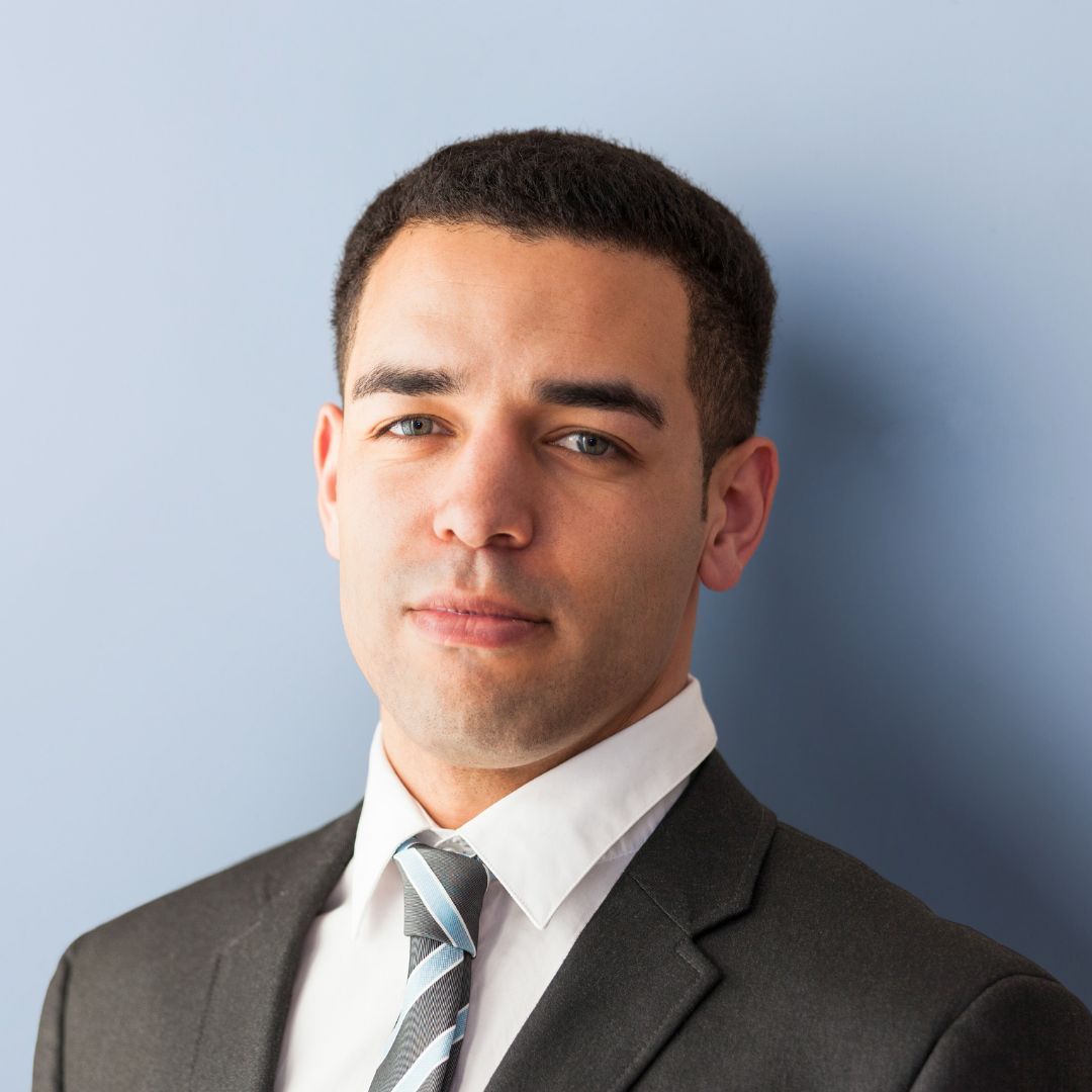 A man in a suit and tie is standing in front of a blue wall