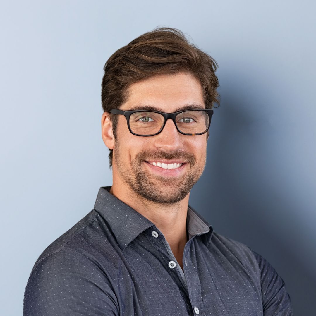 A man wearing glasses and a black shirt is smiling for the camera.