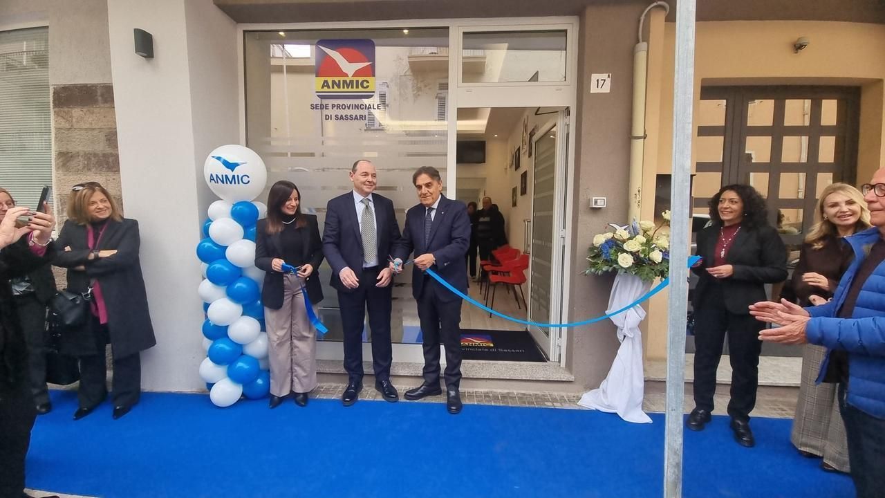 People cut ribbon at a building entrance. Blue and white balloons decorate the opening.