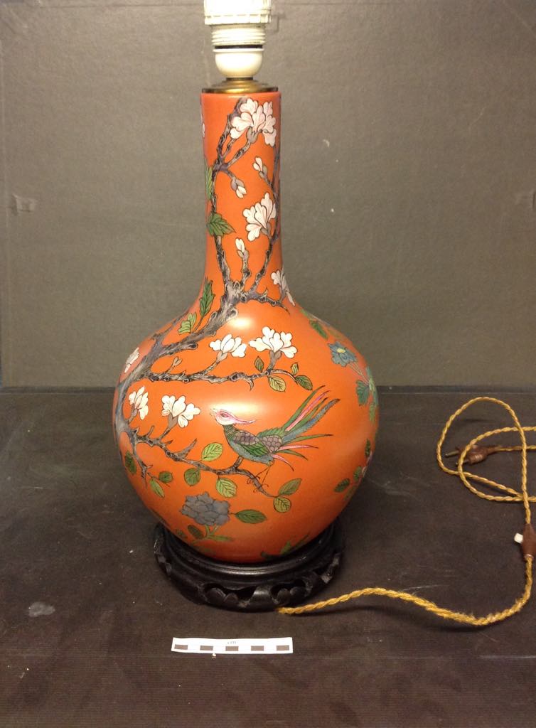 Um vaso laranja com flores e pássaros
