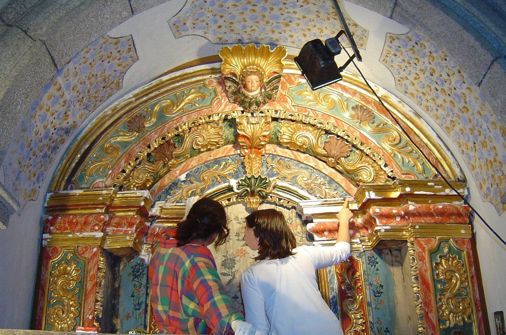 Duas mulheres estão trabalhando em uma pintura em uma igreja