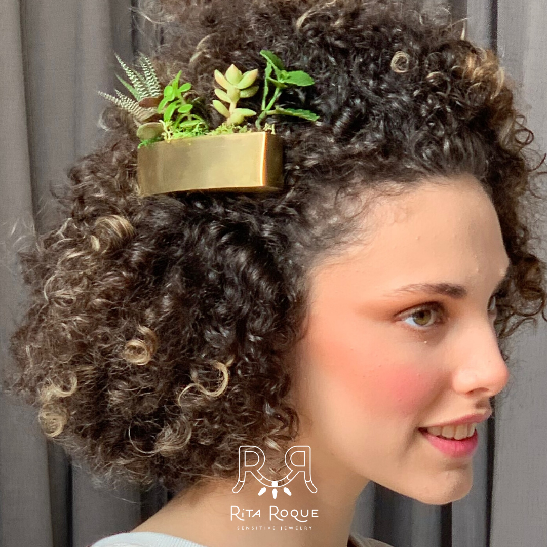Uma mulher com cabelo cacheado tem uma planta no cabelo.