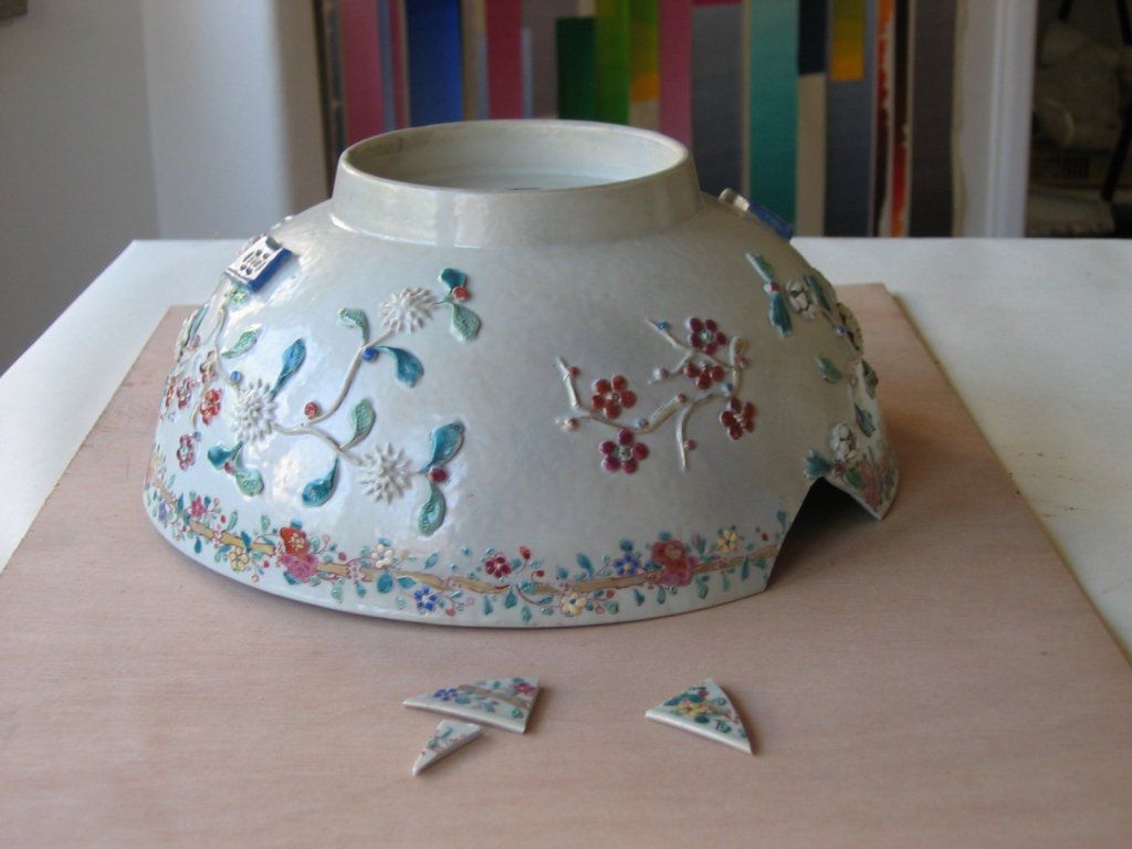 Uma tigela branca com flores está sobre uma mesa de madeira.