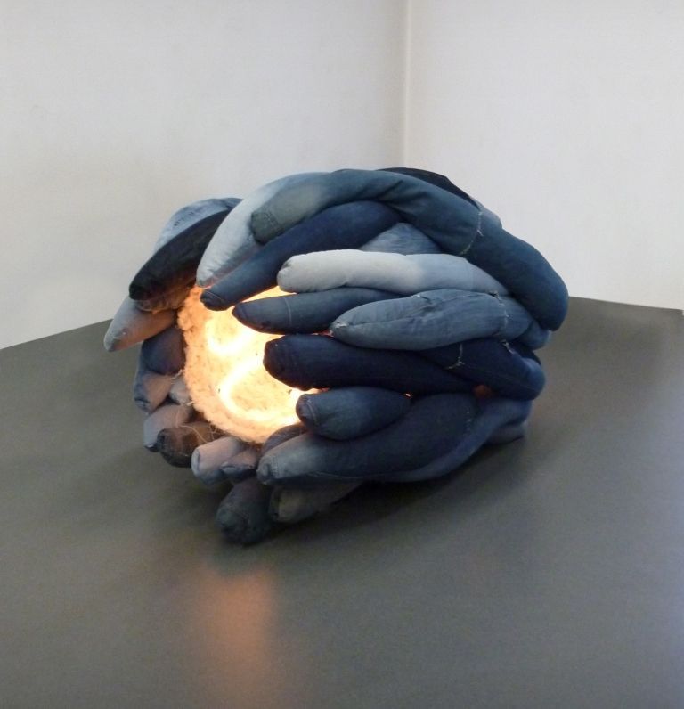 Uma escultura feita de jeans está sobre uma mesa