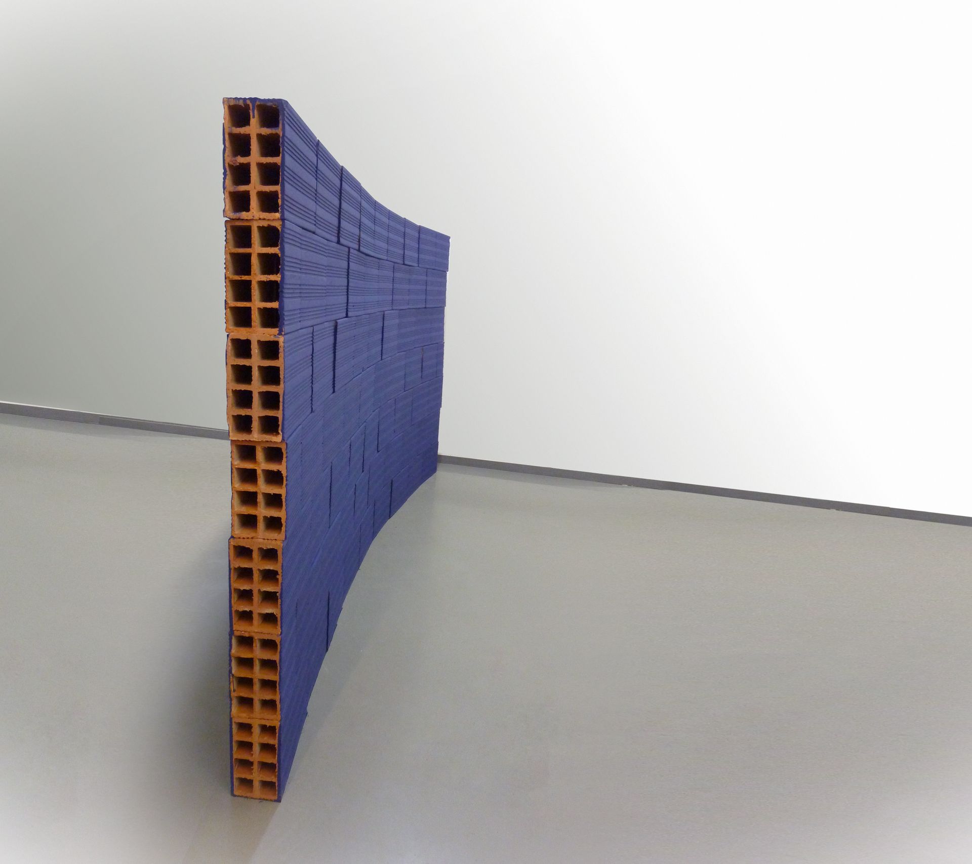 Uma parede de tijolos azuis está sobre um chão cinza