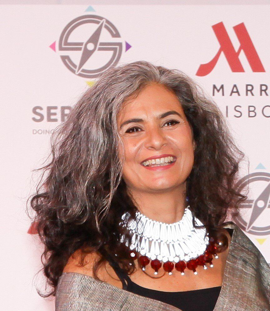Uma mulher de cabelos grisalhos sorri em frente ao logotipo da Marriott