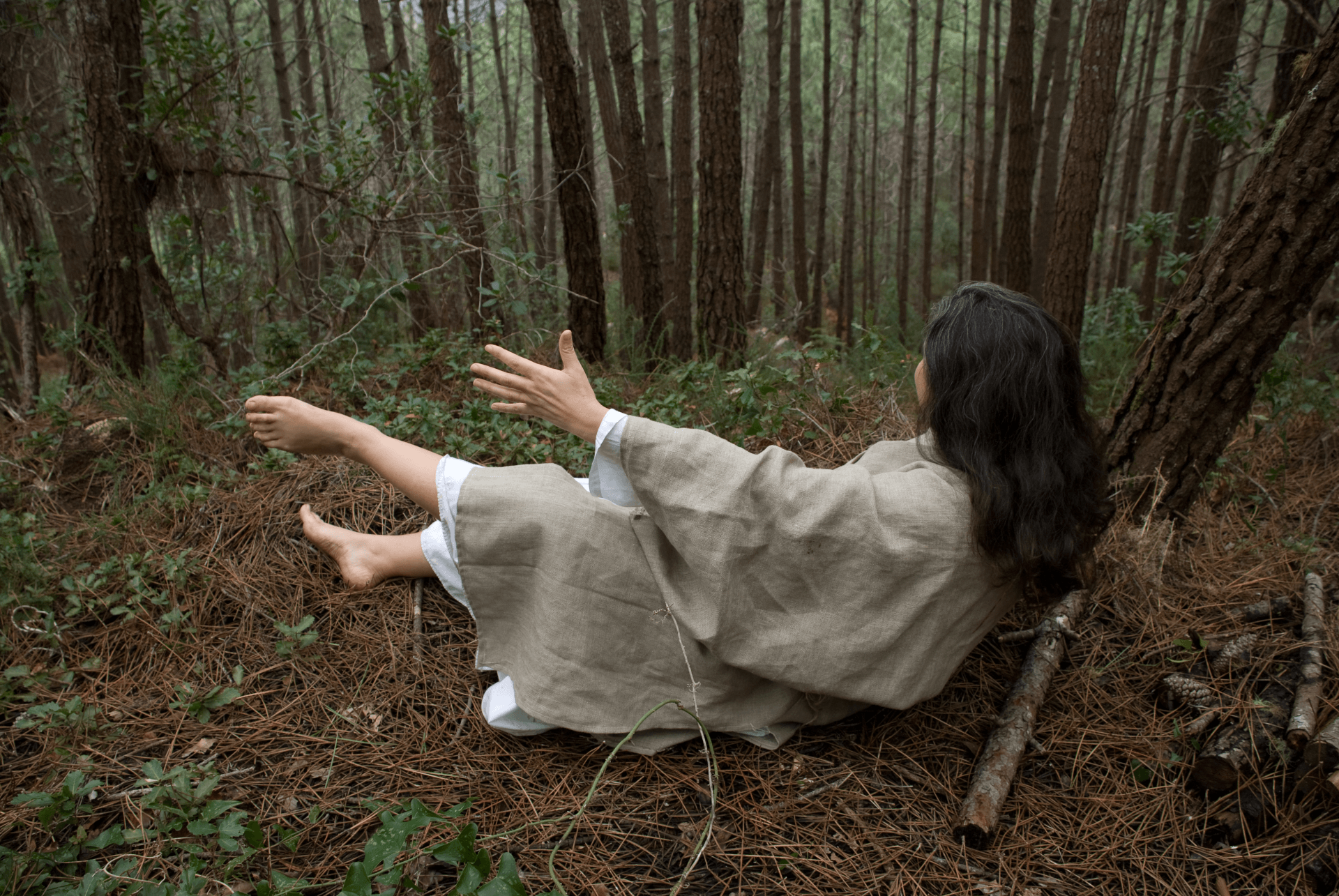 Uma mulher está deitada no chão na floresta.