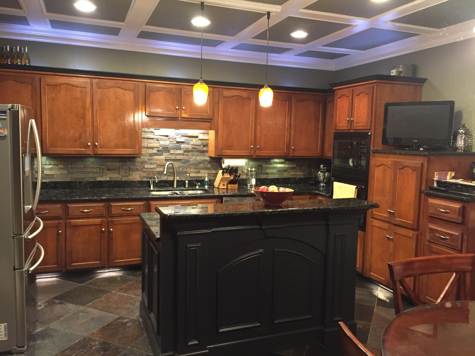 A kitchen with wooden cabinets and a black island