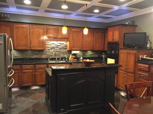 A kitchen with wooden cabinets and a black island