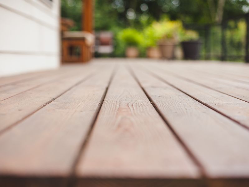 A close up of a wooden deck with a blurred background.