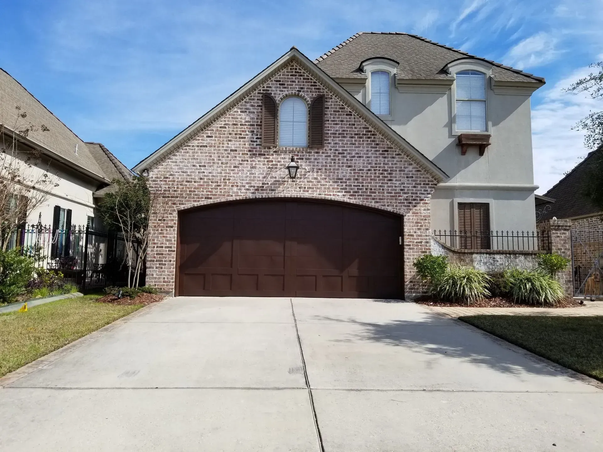 Two-story house with brick garage and stucco siding, driveway, and blue sky.