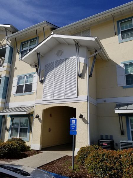 Yellow building entrance with blue handicap sign. White shutters on the building.