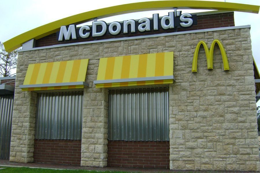 McDonald's restaurant, closed. Exterior view with a stone facade and yellow awning and logo. Windows covered.