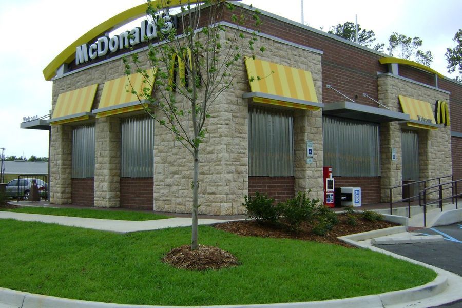 McDonald's restaurant building with yellow awning and sign, beige brick exterior, accessible ramp.