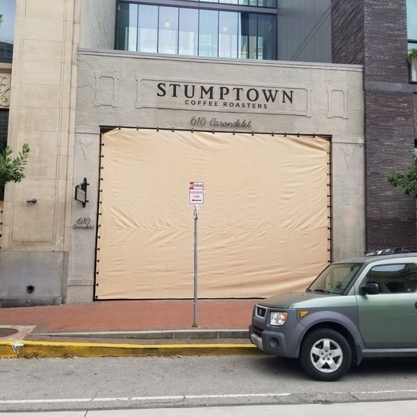 Stumptown Coffee Roasters storefront with tan covering over the entrance; a green SUV is parked on the street.