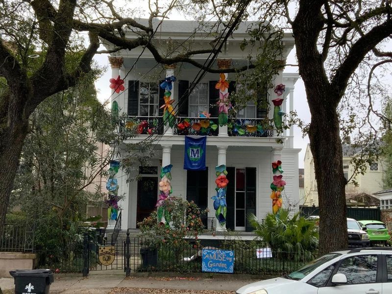 White house with colorful flower decorations on columns, balcony, and windows; street view.