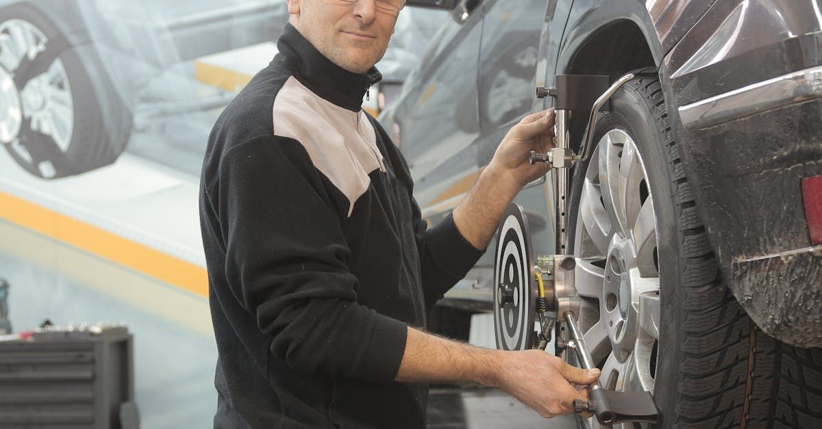 A man is working on a car wheel in a garage.  | Checkered Flag Auto Center