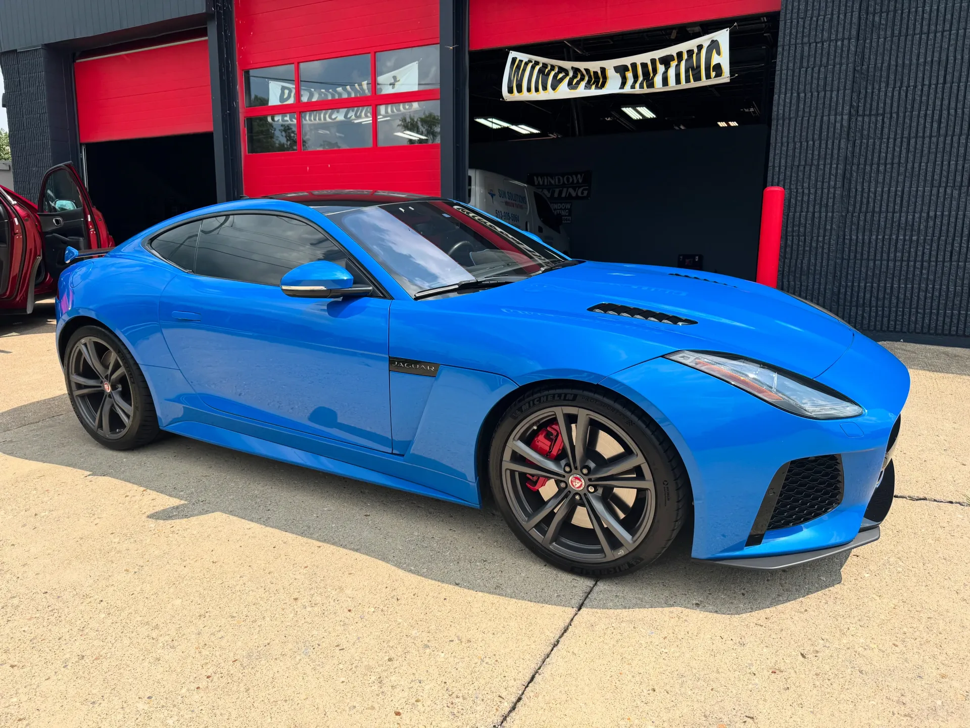 Black Chevrolet Camaro in a garage, black wheels, yellow line on the floor, promotional banners on the wall.
