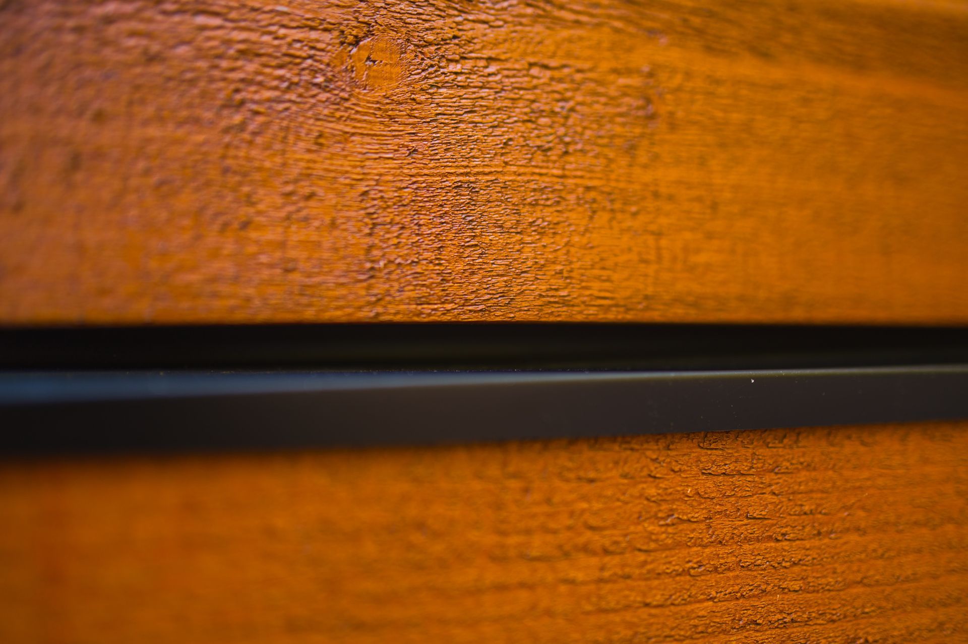 A close up of a piece of wood with a black stripe on it.