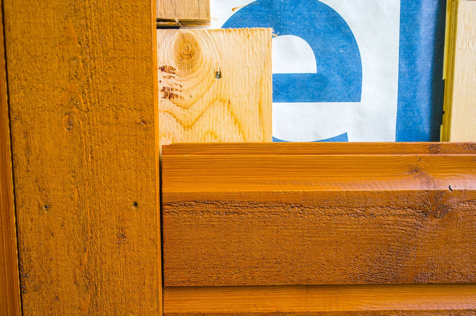 A close up of a piece of wood with a blue and white sign in the background.