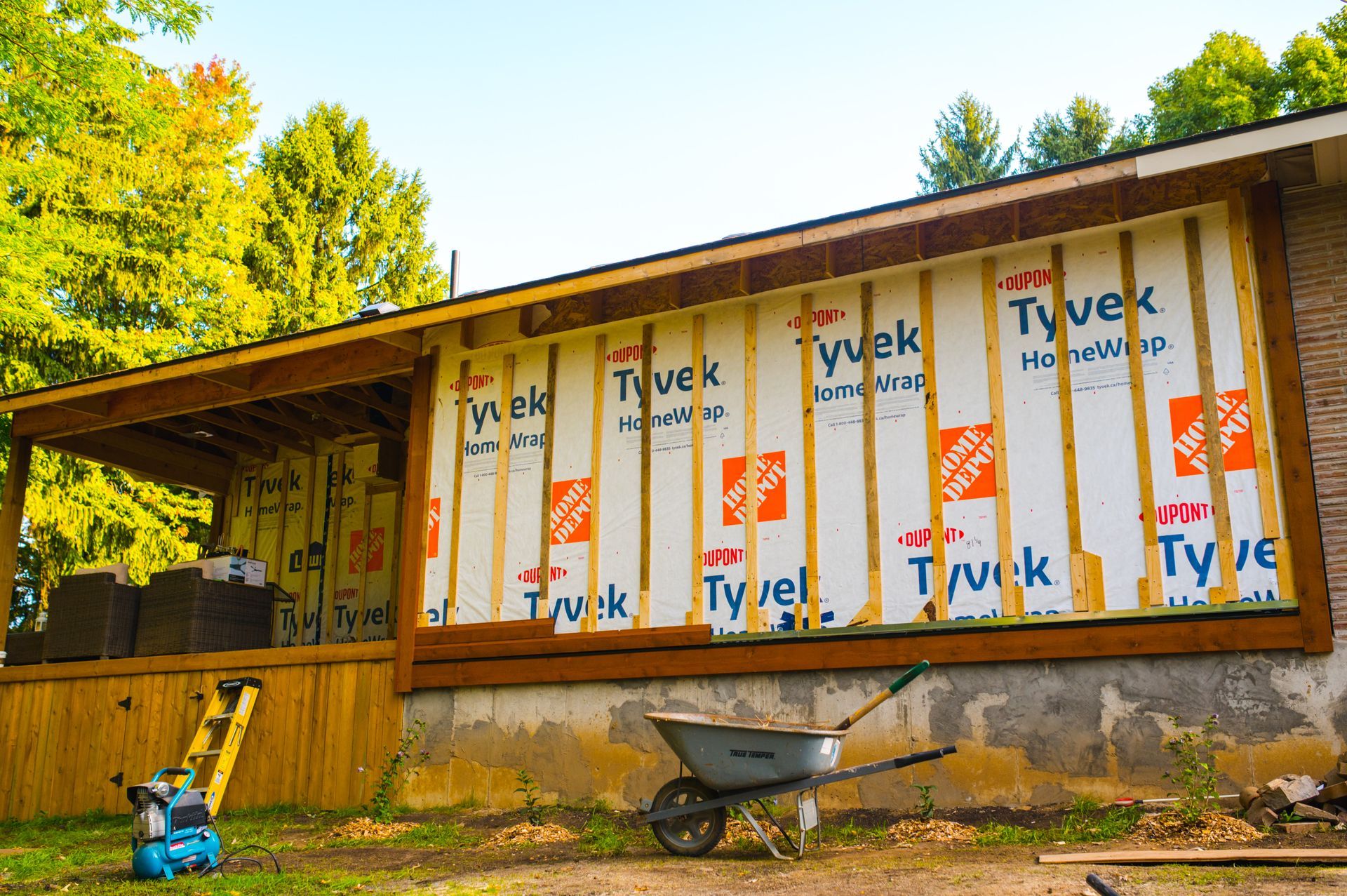A wheelbarrow is parked in front of a house that is being built.