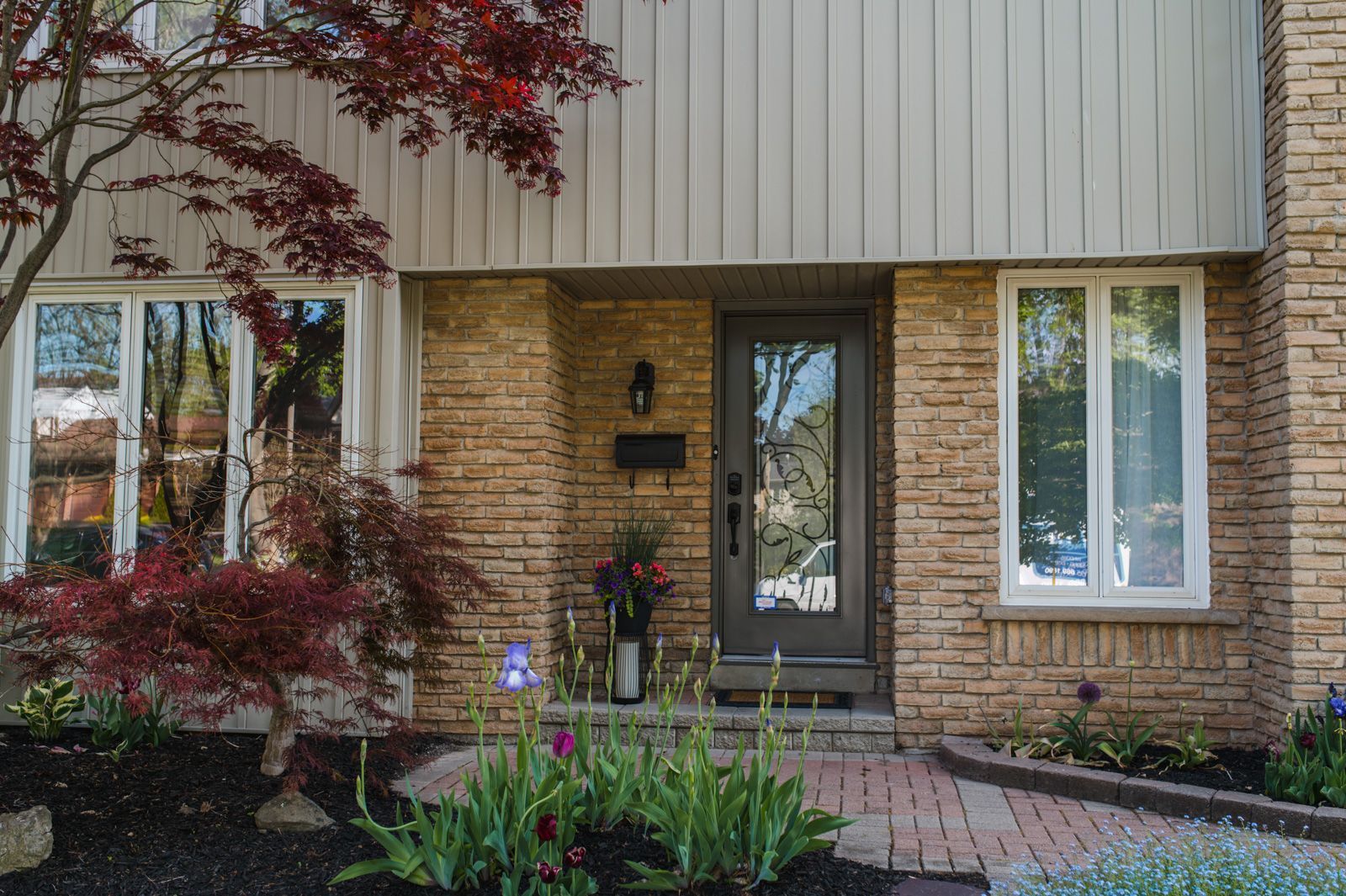 The front of a brick house with a brick walkway leading to the front door.