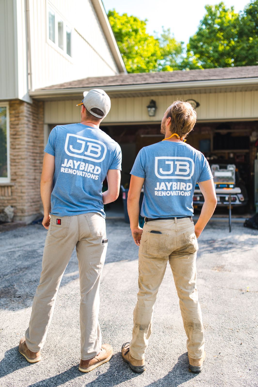 Two men are standing next to each other in front of a garage.