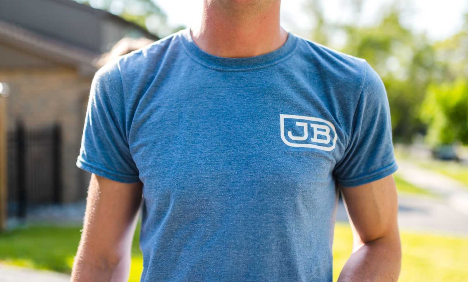 A man wearing a blue t-shirt is standing on a sidewalk.
