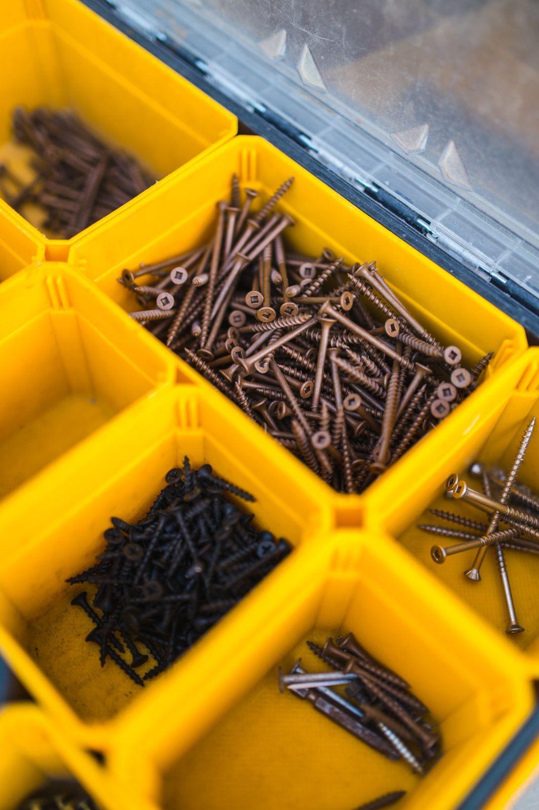A yellow plastic container filled with nails and screws.