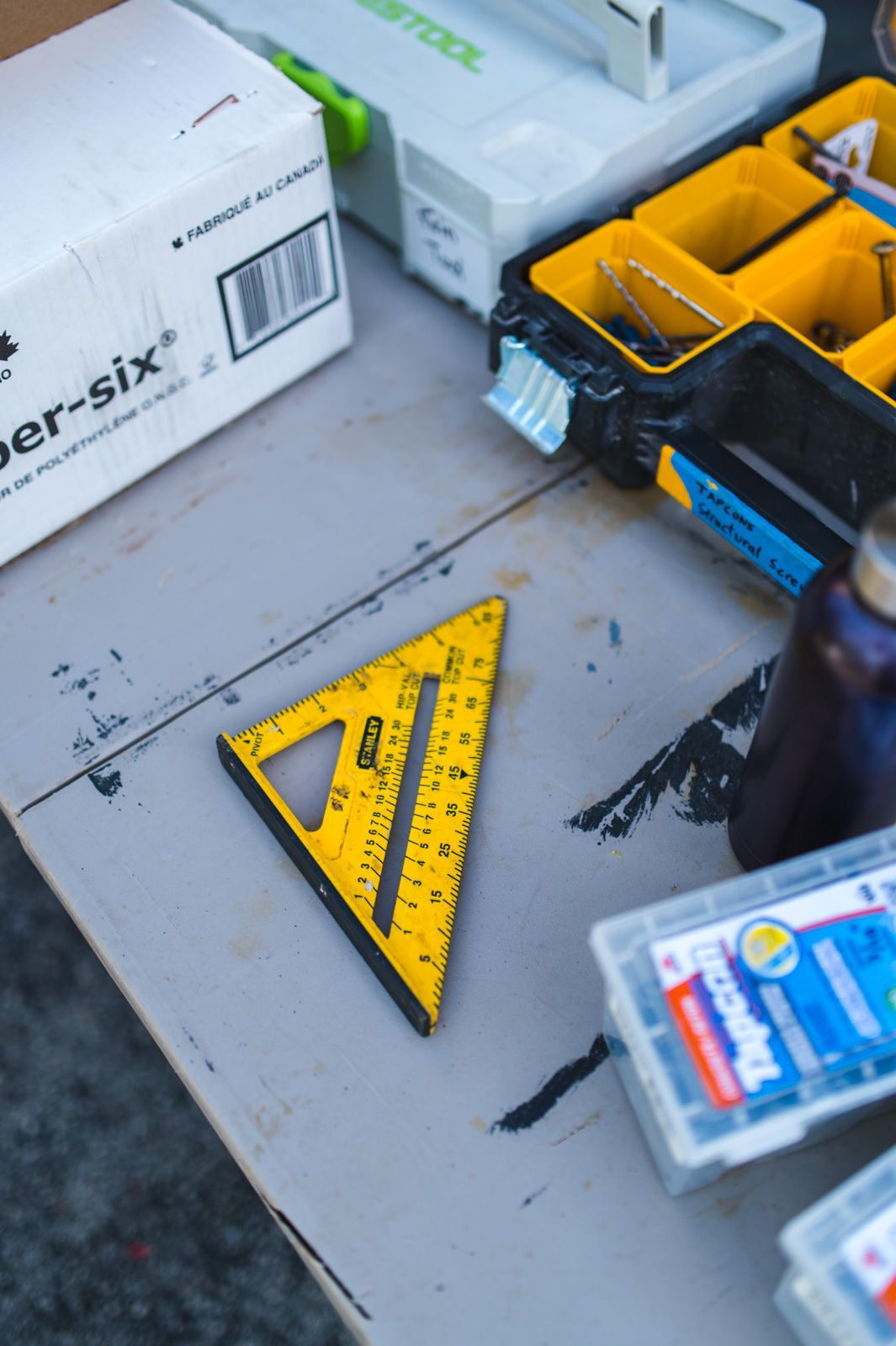 A yellow ruler sits on a table next to a box that says per-six