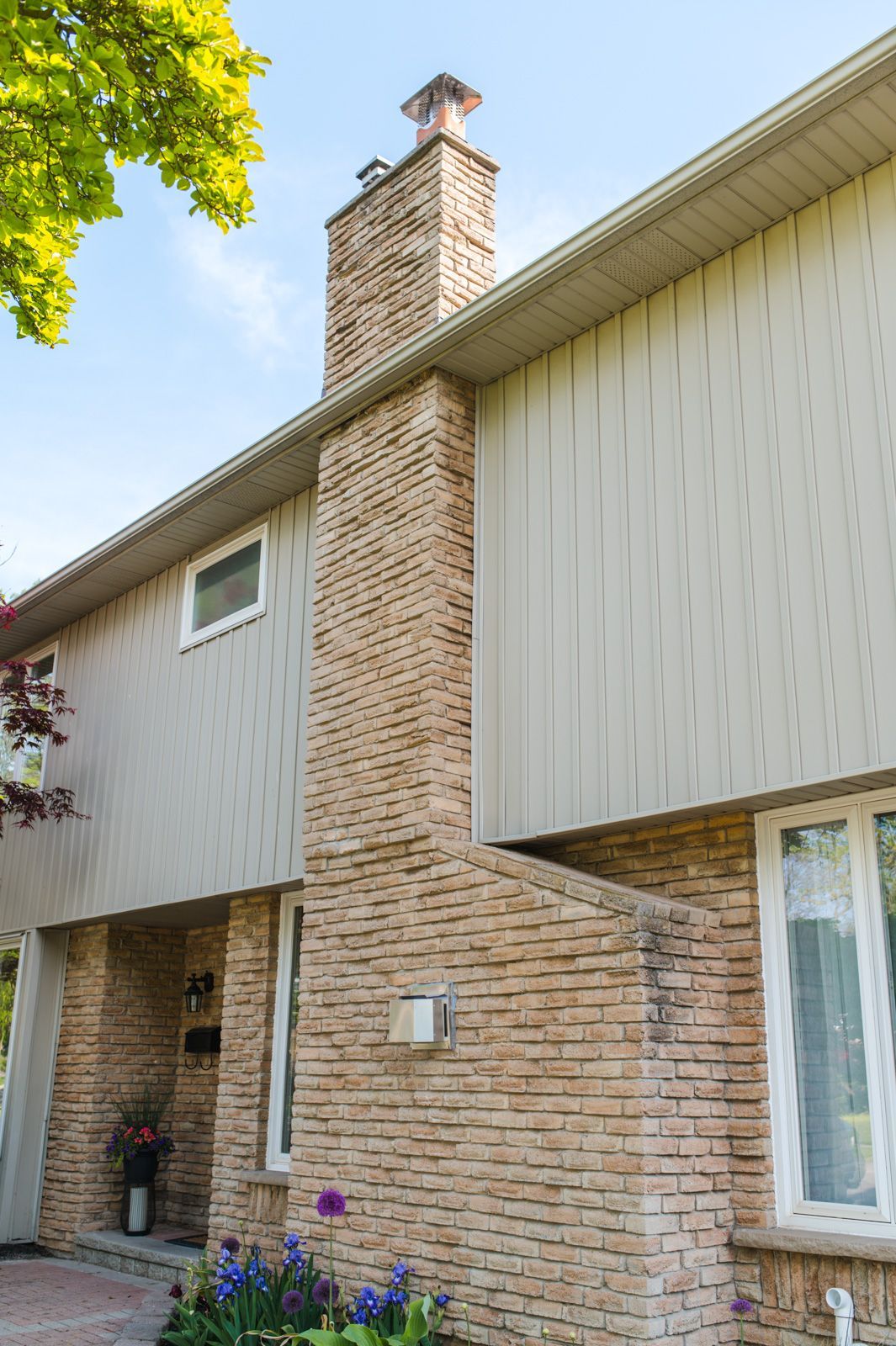 A brick house with a chimney on the side of it.