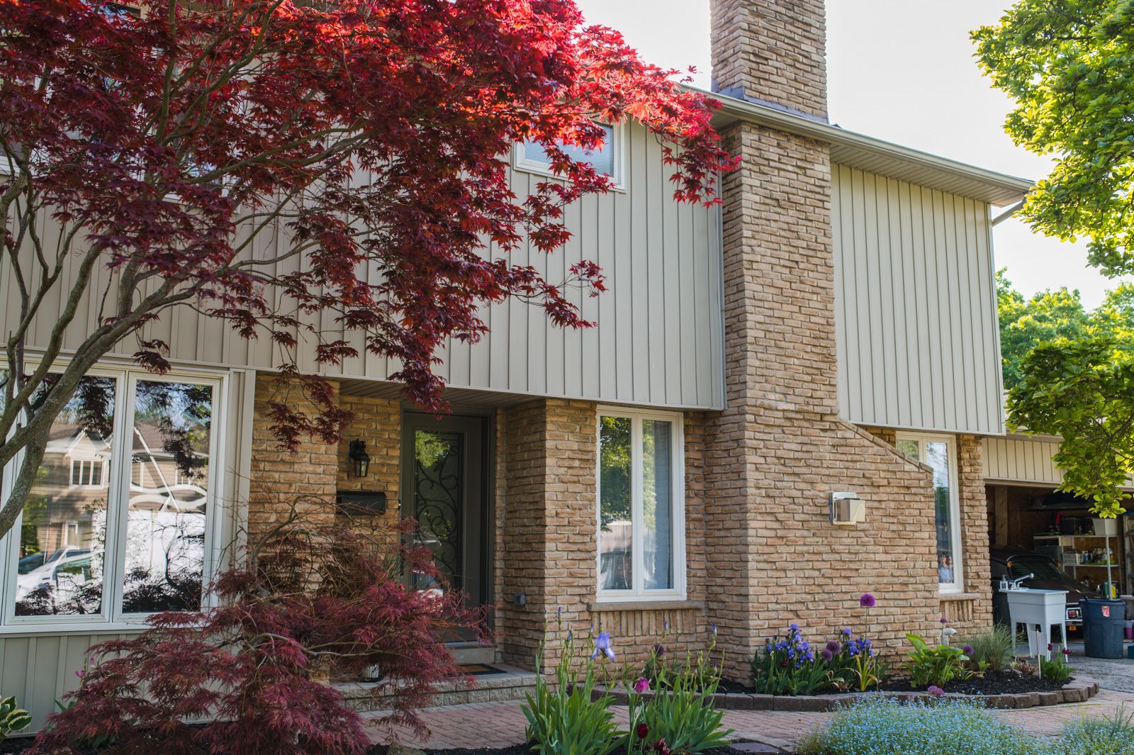 A brick house with a lot of windows and a tree in front of it.
