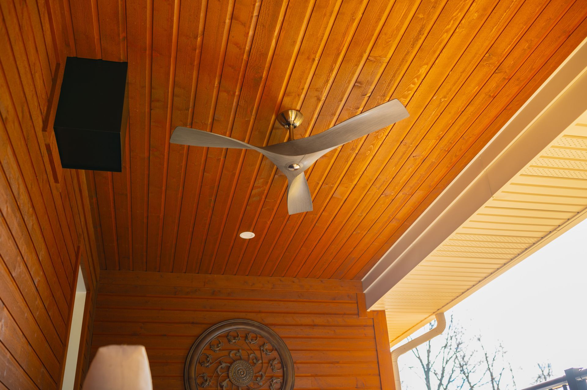 A ceiling fan is hanging from the ceiling of a wooden porch.