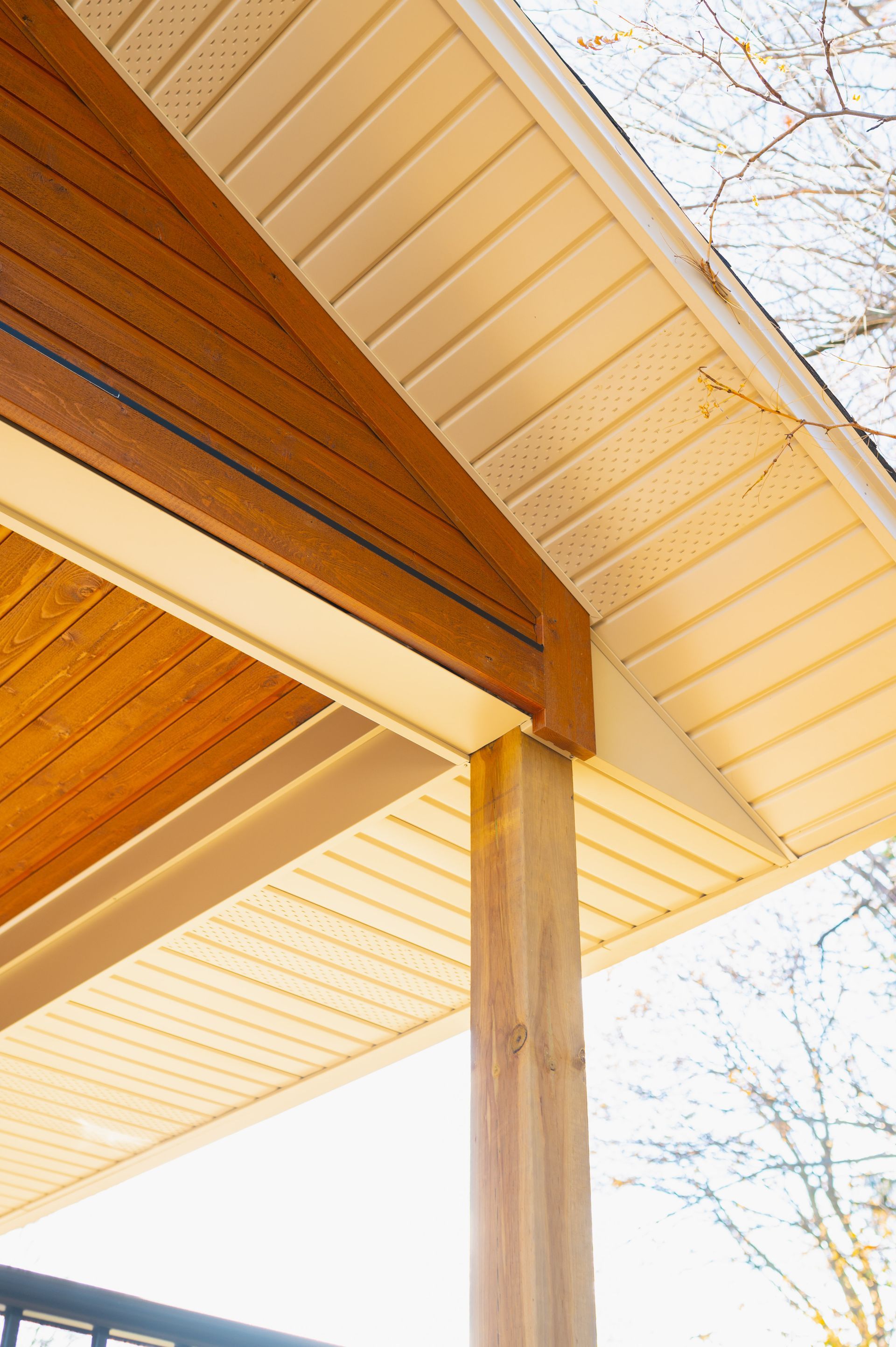 A close up of a porch with a wooden roof and white siding.