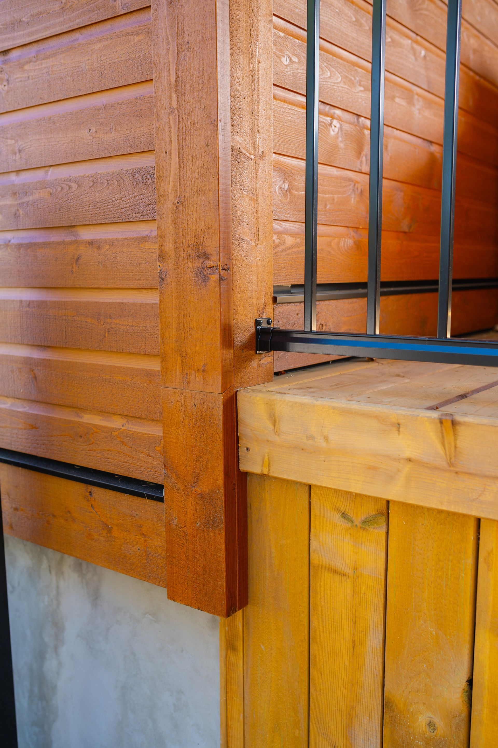 A wooden deck with a metal railing on the side of a house.